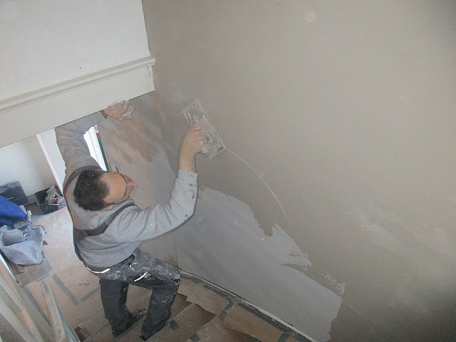 ISOTEC-Mitarbeiter verputzt die mit Klimaplatten gedämmte Wand Nachdem die kalten Wände mit ISOTEC-Klimaplatten gedämmt wurden, werden sie im letzten Arbeitsschritt mit einer Kalkglätte verputzt