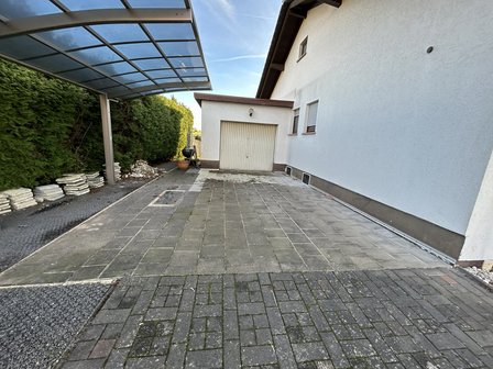 Gepflasterte Einfahrt mit Carport, Garage und gestapelten Platten