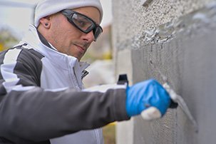 ISOTEC Mitarbeiter trägt Außenabdichtung auf