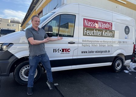 Person zeigt auf ISOTEC‑Firmenfahrzeug auf Parkplatz