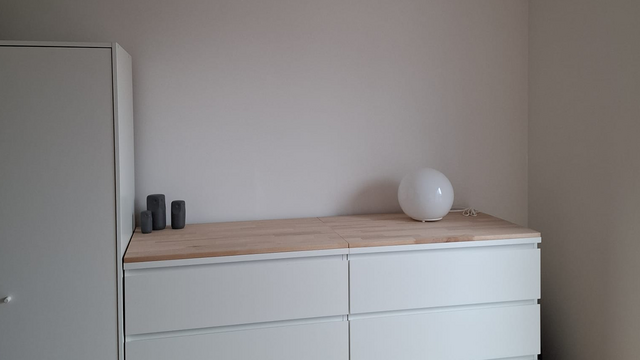 Weiße Kommode mit Holzplatte und runder Lampe