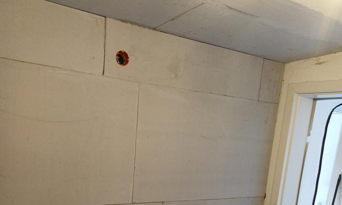 Wand mit hellen Platten und sichtbaren Fugen neben Türöffnung