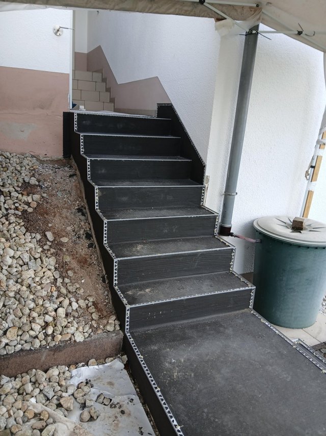 Schwarze Treppenstufen mit Kantenprofilen an Hauseingang im Außenbereich