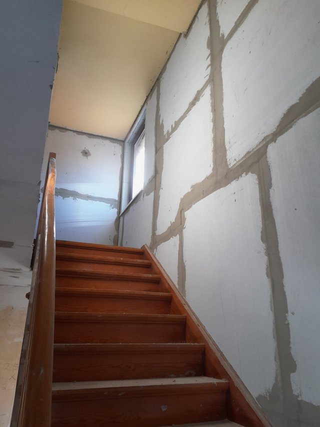 Holztreppe vor Wand mit beigespachtelten Fugen