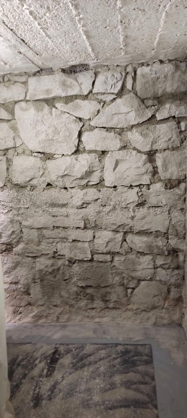 Bröckelige Kellerwand aus hellem Bruchsteinmauerwerk, Nahaufnahme.