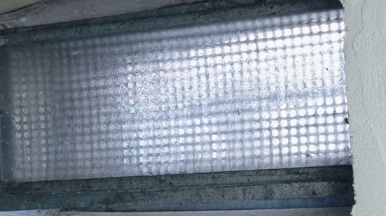 Kelle mit grauer Masse auf weiß beschichteter Fensterlaibung