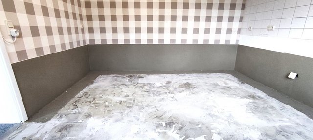 Unrenovierter Raum mit grauer Wandfläche und rohem Boden