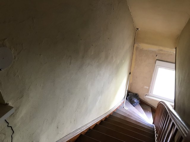 Abgenutztes Treppenhaus mit rissigen Wänden und Fenster