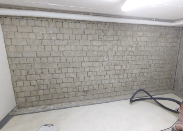 Kellerraum mit freigelegter Ziegelwand und Bohrlochreihe unter der Decke