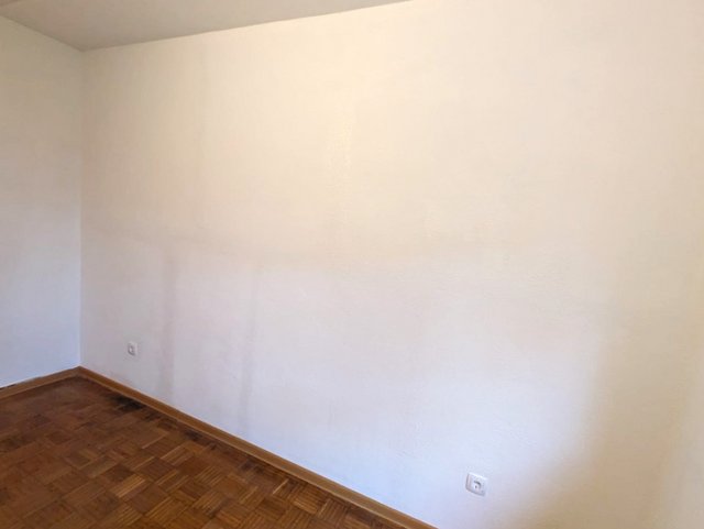 Leere Zimmerwand mit weißen Flächen und Parkettboden, Innenraumansicht