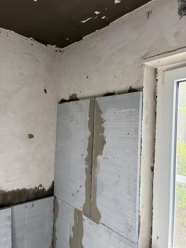 Helle Platten an Raumecke montiert, graue Masse in Fugen und Kanten aufgetragen.
