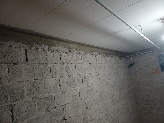Graue Masse entlang Kellerwand unter weißer Betondecke