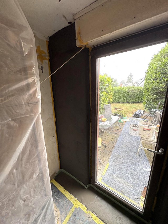 Schwarze Masse an Wand neben Terrassentuer, Boden mit Folie und Klebeband abgeklebt.