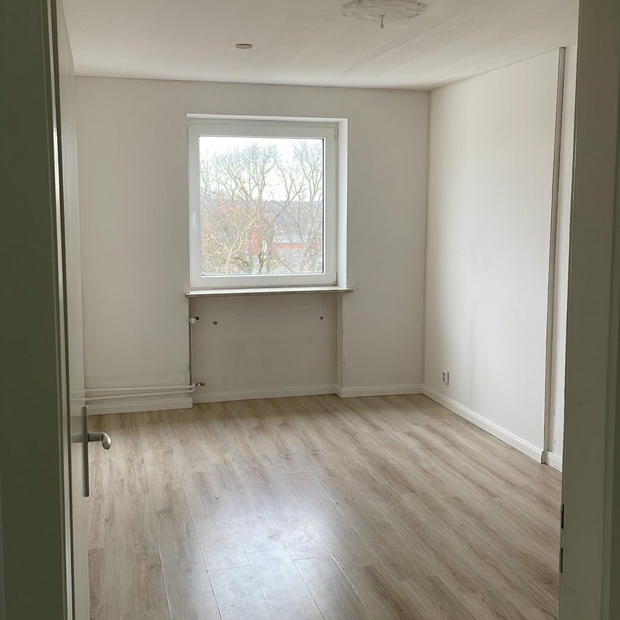 Leerer heller Raum mit Fenster und hellem Laminatboden