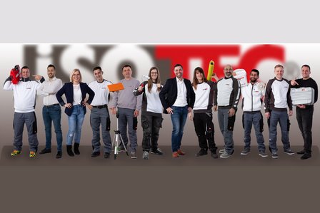 ISOTEC Team steht in Reihe und zeigt Werkzeuge wie Bohrhammer, Rolle, Eimer und Koffer