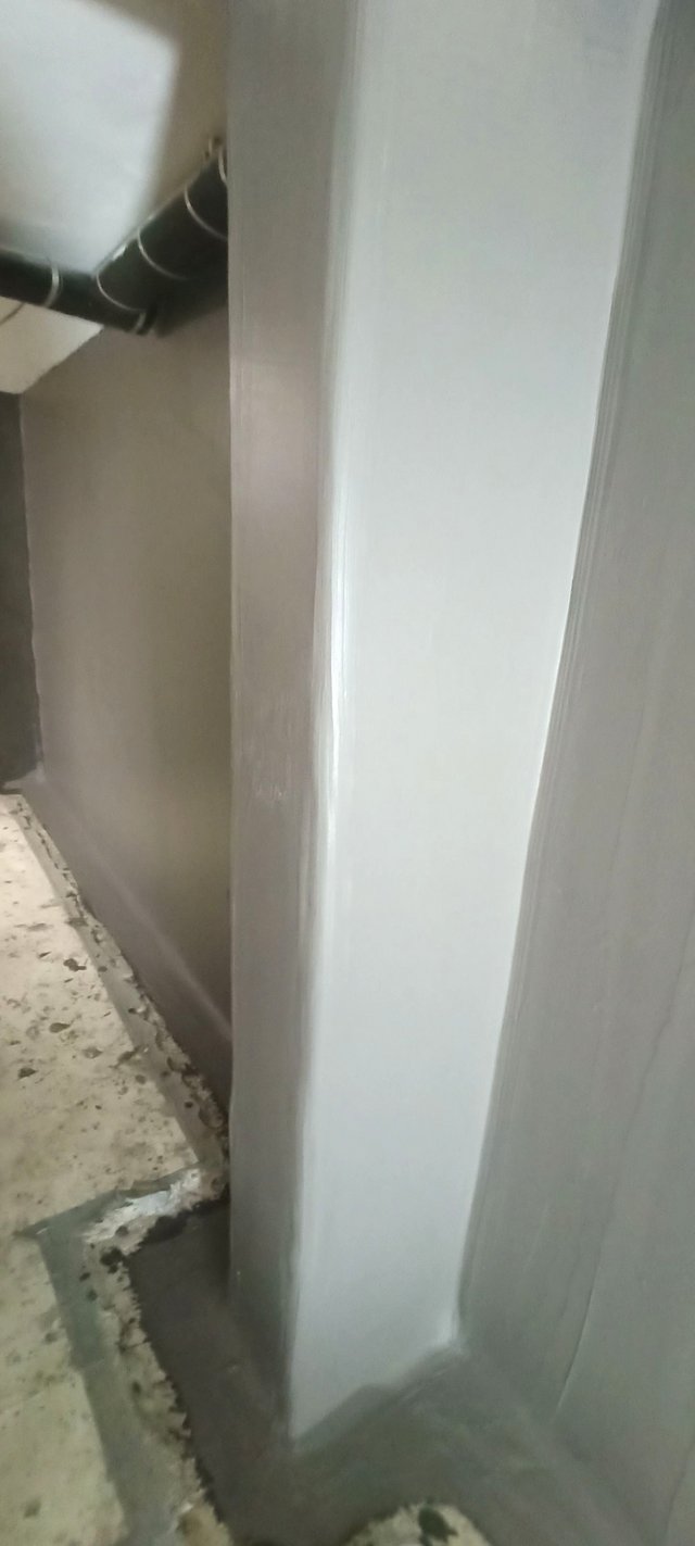 Grau beschichtete Wandfläche mit abgedichteter Bodenkante