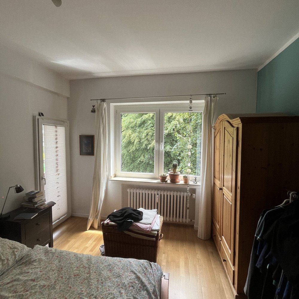 Schlafzimmer mit Bett, Holzschrank und Fensterfront, Tageslicht