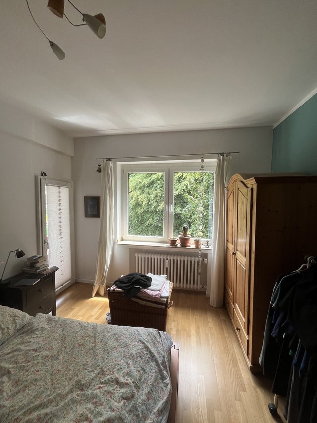 Schlafzimmer mit Bett, Holzschrank und Fensterfront, Tageslicht