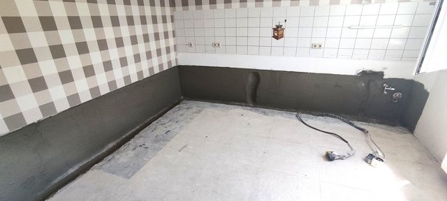 Dunkle Masse auf unterem Wandbereich in leerem Raum