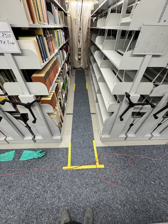 Schmale Gasse zwischen Rollregalen mit Büchern und leeren Fachböden