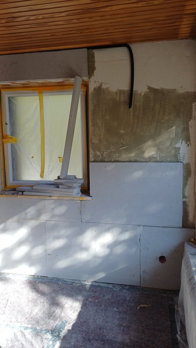 Abgeklebtes Fenster mit heller Platte und grauer Masse an der Wand