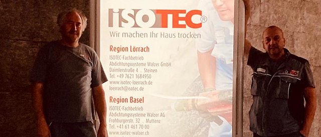 Dietmar Feix und Alexander Gross setzen unser neues ISOTEC Werbeschild in einer Tiefgarage in Lörrach in Szene