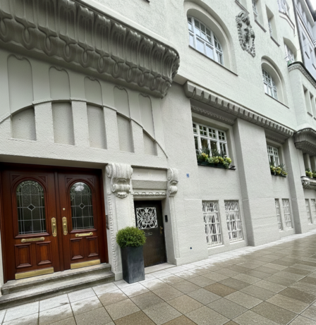 Verzierte Hausfassade mit Holztüren, Fenstern und Blumenkästen.