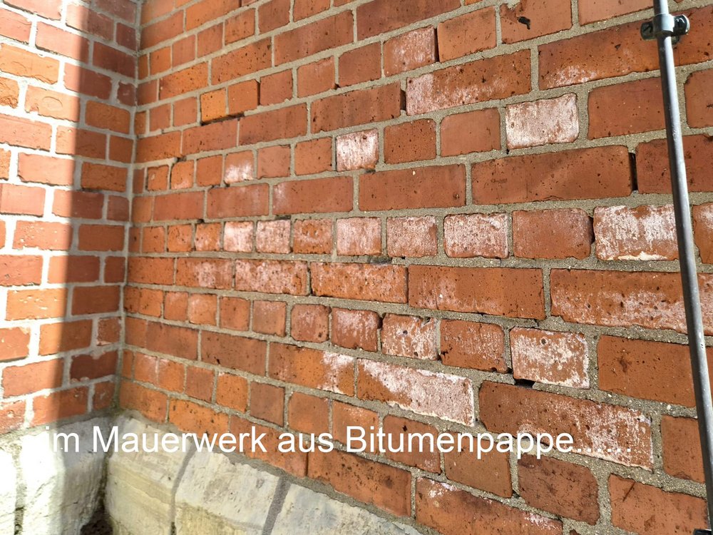 Ziegelmauerwerk mit weißen Ausblühungen und grauer Sockelzone, Eckansicht