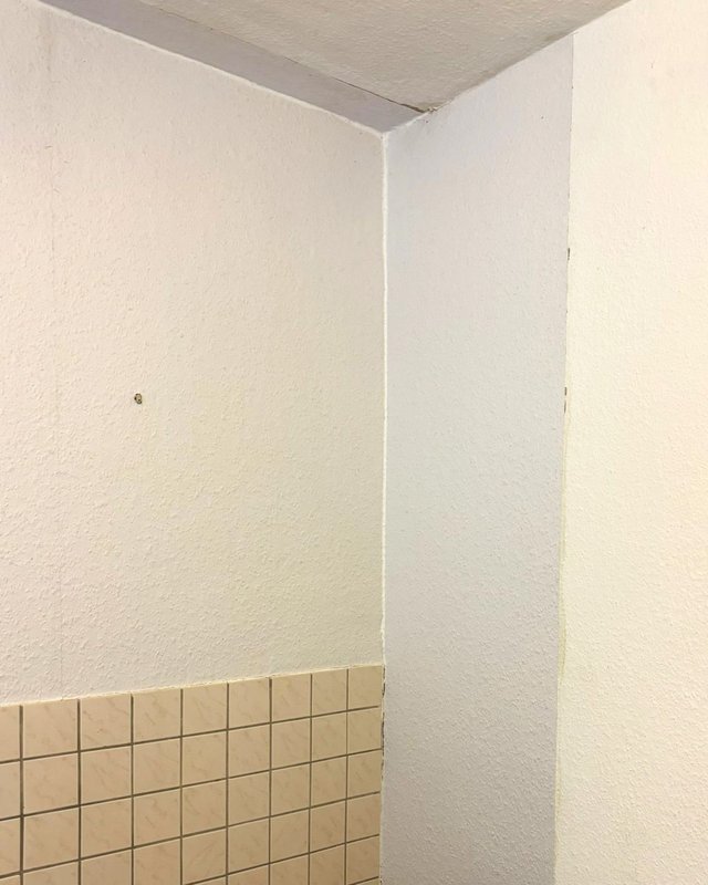 Helle Wandecke über Fliesenspiegel mit feinen Verfärbungen an der Deckenfuge