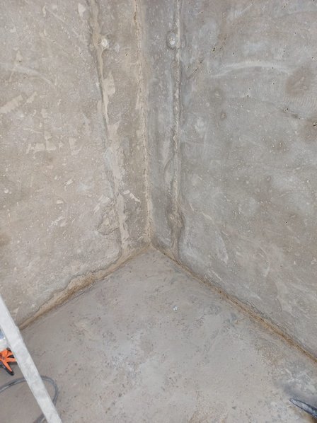 Raue Betonwand mit sichtbarer Fuge im Wand‑Boden‑Übergang