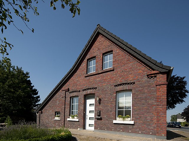 Backsteinfassade eines Wohnhauses mit weißen Fenstern bei Sonnenschein