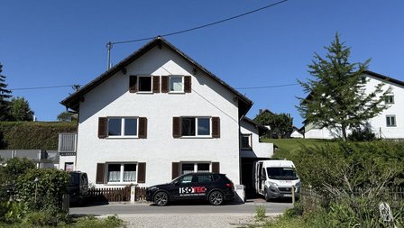 ISOTEC Fahrzeuge vor weißem Wohnhaus mit Garten und Zufahrt