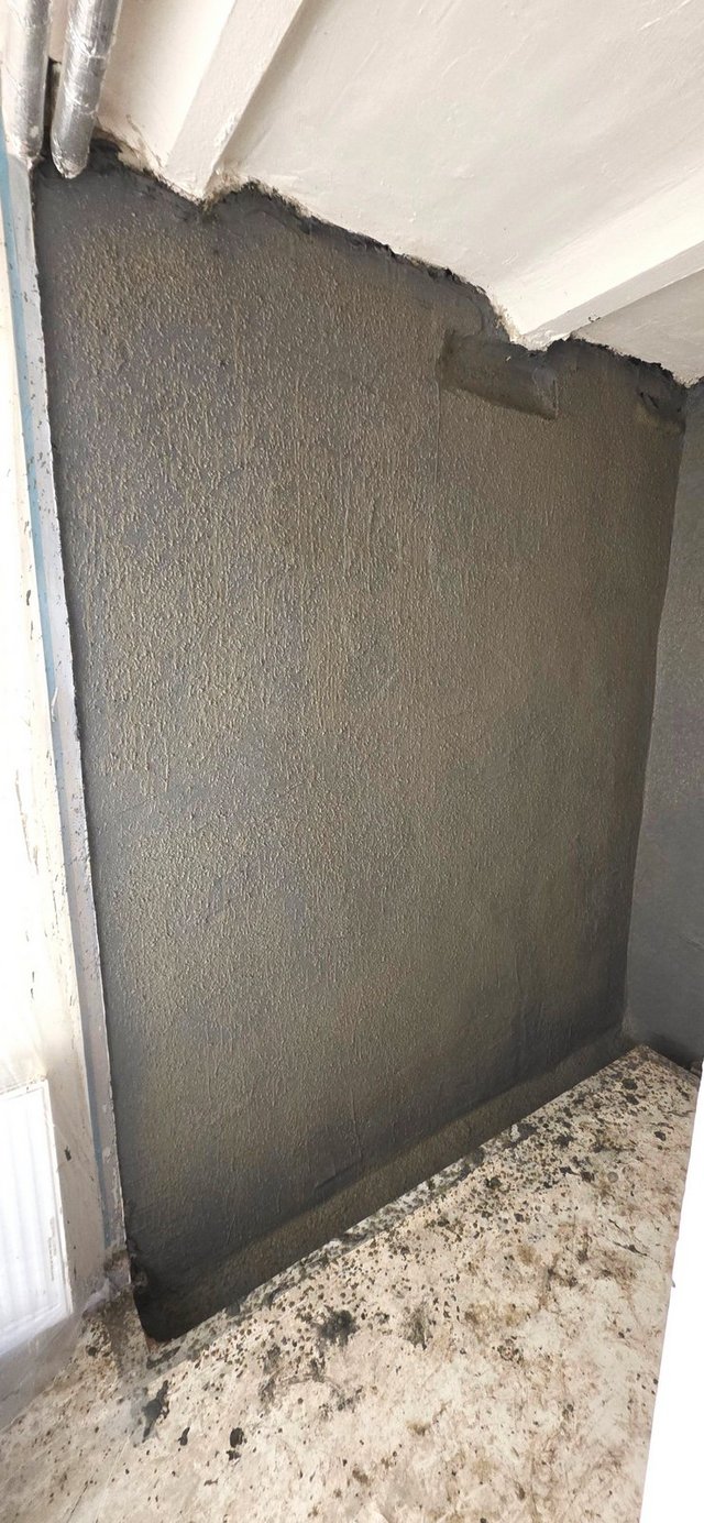 Schwarze Masse auf Wandfläche in Raumecke aufgetragen