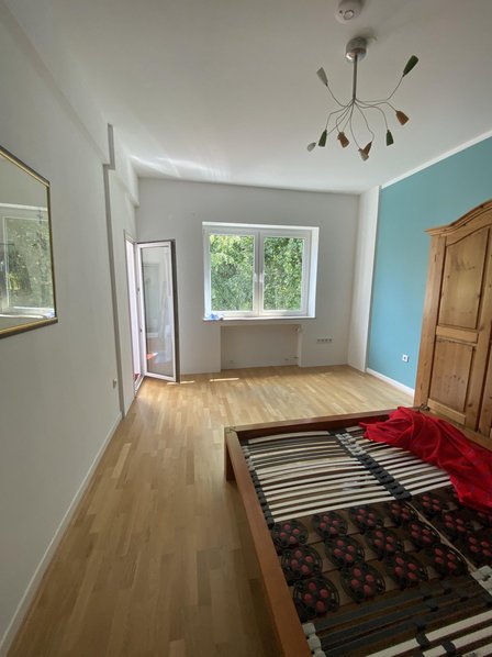 Schlafzimmer mit Holzfußboden, Bettgestell, Fenster und blauer Wand