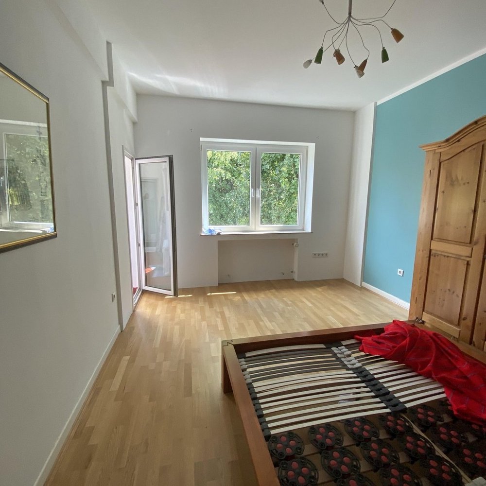 Schlafzimmer mit Holzfußboden, Bettgestell, Fenster und blauer Wand