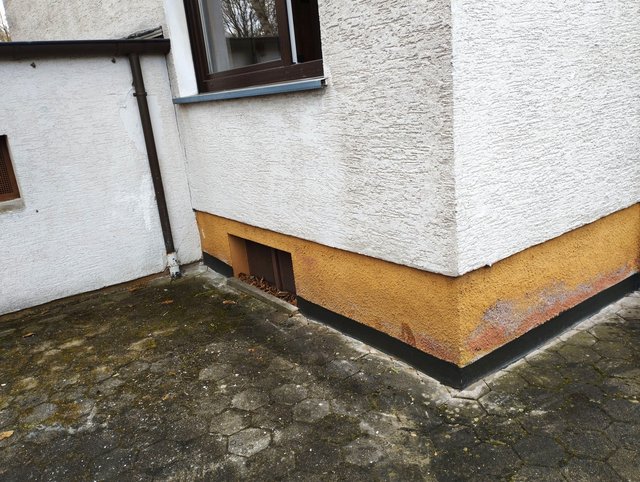 Verfärbte Sockelzone an Gebäudeaußenecke