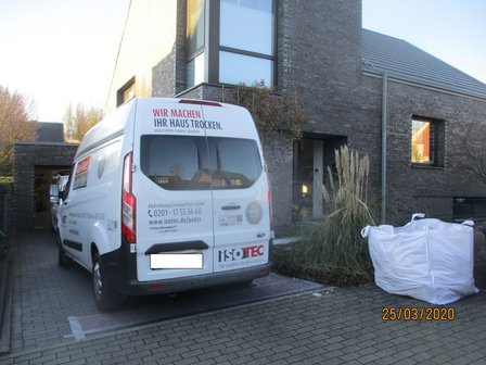 ISOTEC Transporter steht vor Backsteinhaus, daneben weißer Big-Bag auf Pflaster.