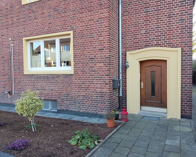 Backsteinfassade mit Haustur, Fenster und gepflastertem Eingangsweg