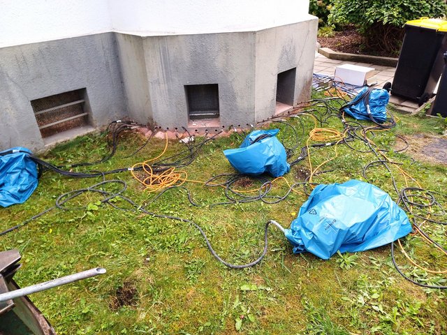 Kabel und Schläuche vor Kellerwand eines Gebäudes