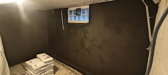 Dunkle beschichtete Kellerwand mit Glasbausteinfenster