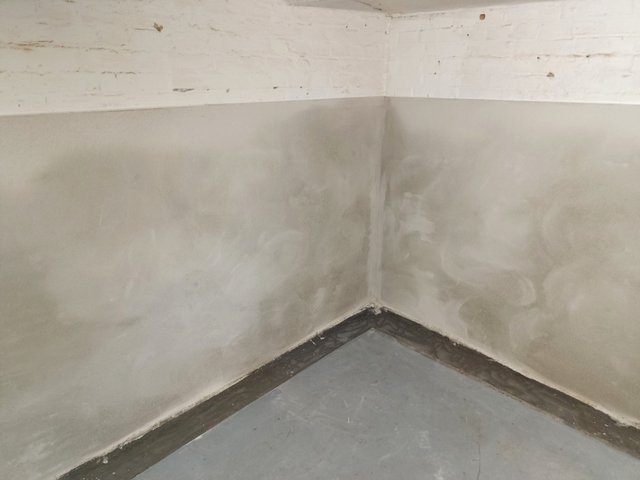 Helle Wandbeschichtung in Kellerecke, schwarze Masse am Bodenanschluss