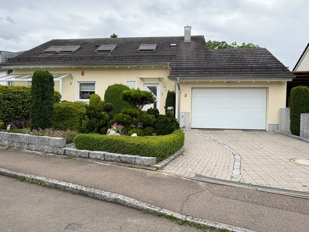 Einfamilienhaus mit Garage, dunklem Ziegeldach und gepflegtem Vorgarten an der Straße