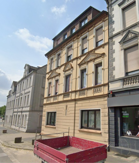 Mehrstöckiges Wohnhaus mit verzierter Fassade an einer Straße