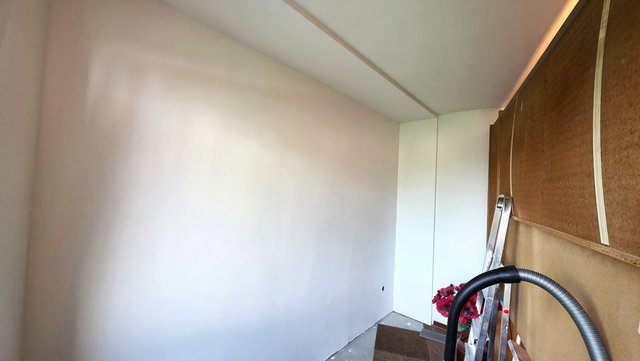 Glatte helle Wand in schmalem Zimmer, Renovierung mit Leiter und Schlauch