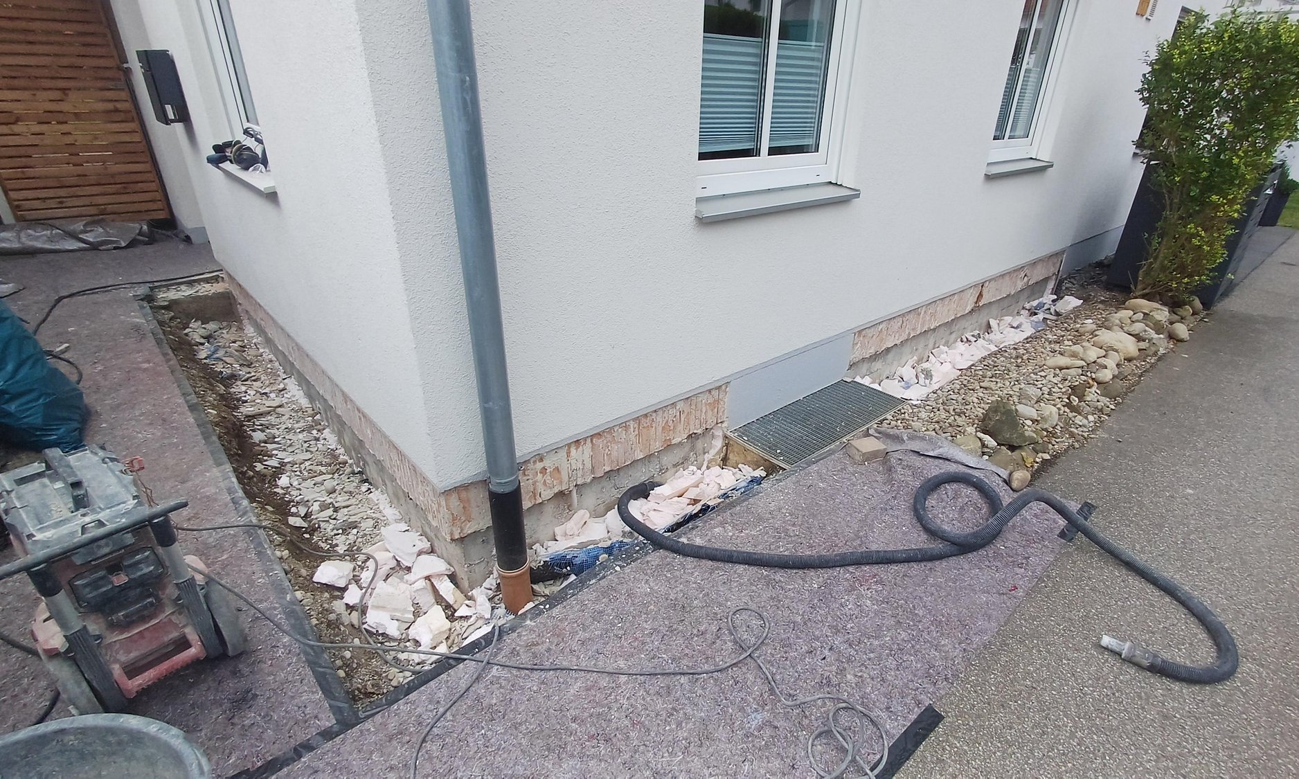 Freigelegter Sockelbereich am Haus mit Bauschutt und Werkzeugen