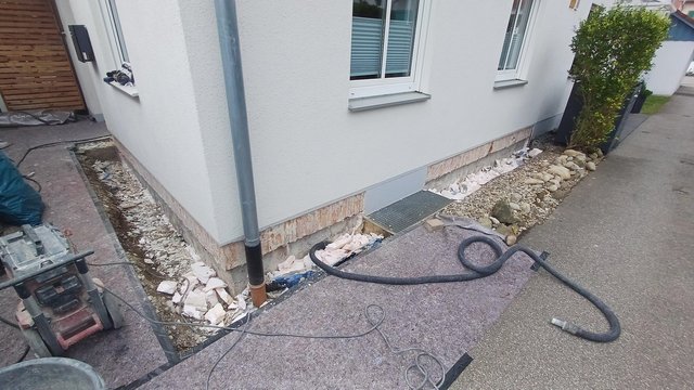 Freigelegter Sockelbereich am Haus mit Bauschutt und Werkzeugen