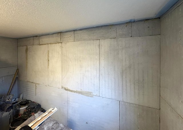 Helle Platten an Kellerwand mit feuchten Laufspuren, Werkzeuge im Vordergrund
