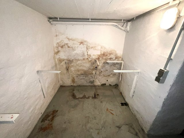 Feuchte Kellerwand mit starken Verfärbungen und Metallhaltern