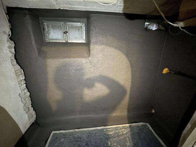 Dunkle beschichtete Kellerwand mit kleinem Fenster.