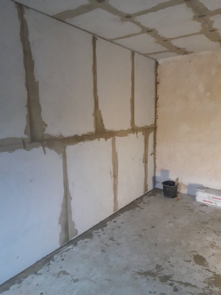 Wand mit hellen Platten und braunen Fugen in leerem Raum